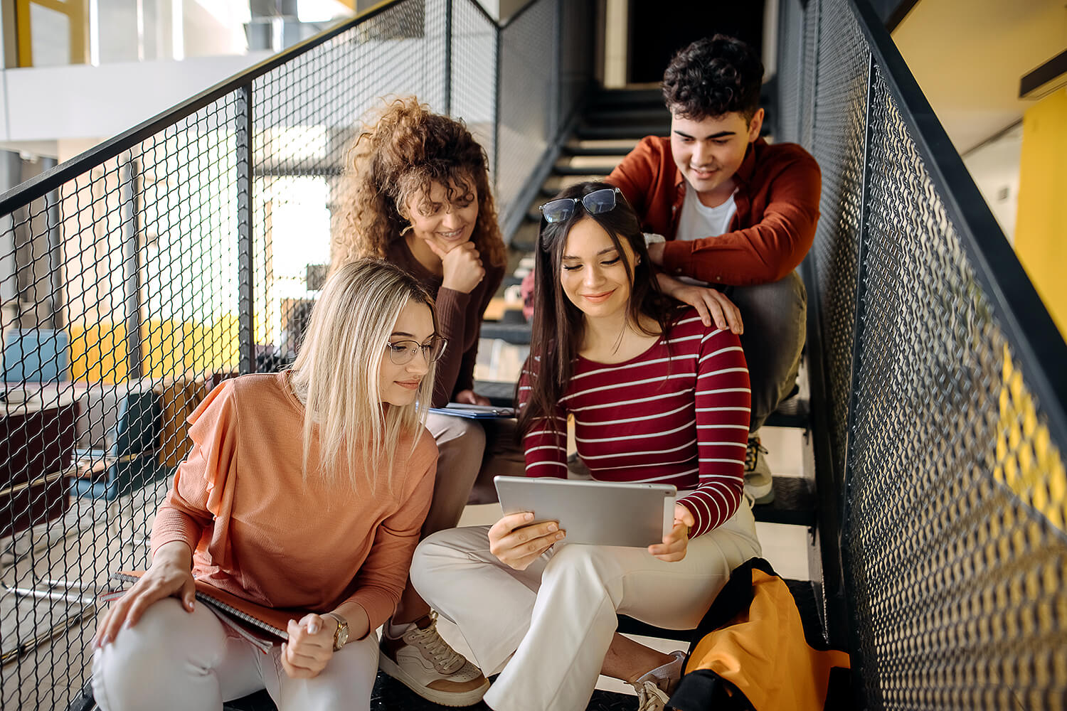 Jugendliche Schülerinnen und Schüler beim digitalen Lernen auf einer Treppe